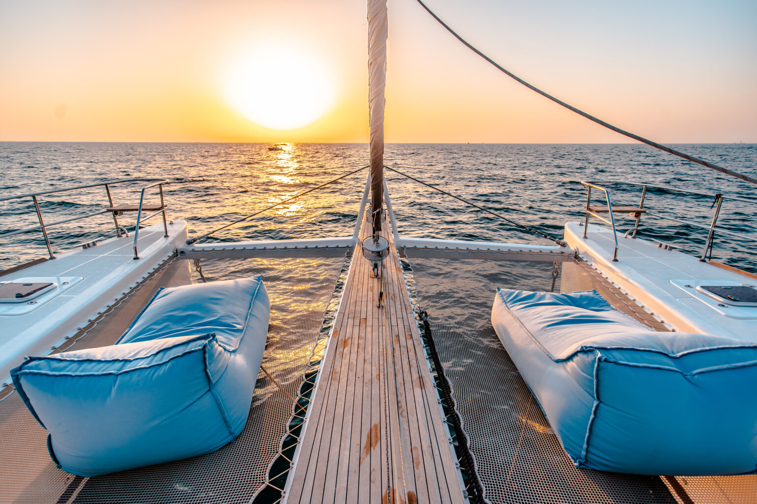 Sunset from a sailing catamaran in the sea with front sitting area